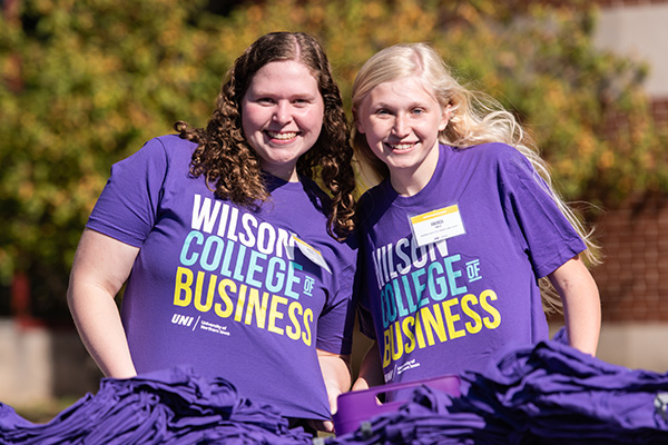 Two students handing out Wilson College of Business shirts.