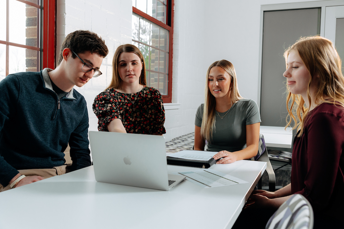 Business students sitting around a laptop