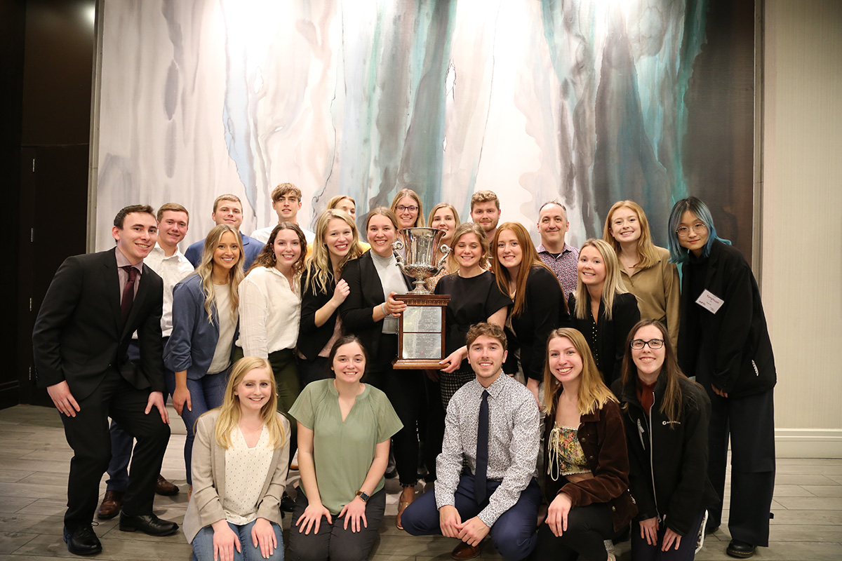 Students and faculty posing with a trophy after a competition.
