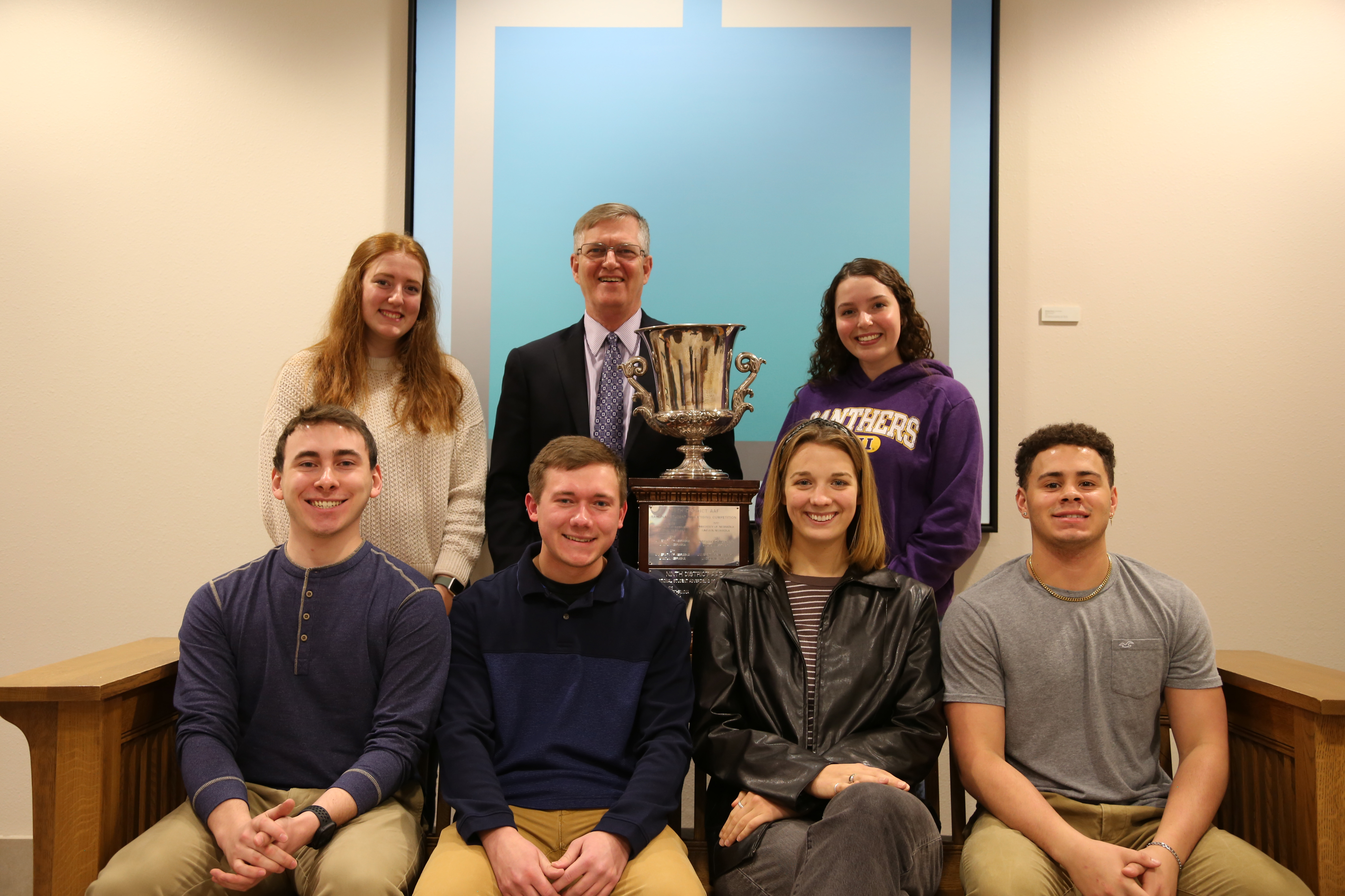 Students and President Nook posing with a trophy after a competition.