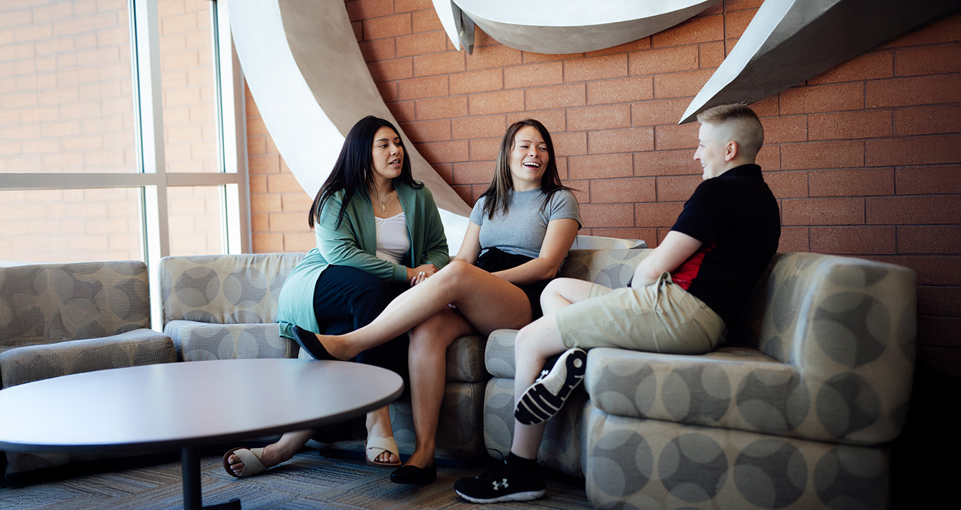 Students having a casual discussion while sitting together in a campus lounge area.
