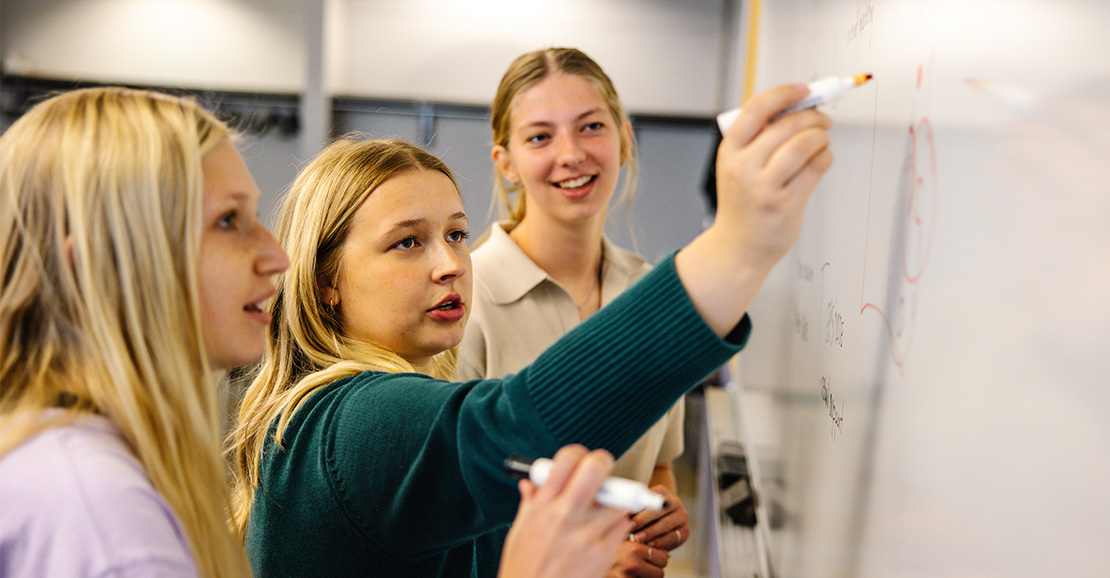 Marketing students writing on whiteboard. 